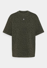 Camiseta verde oliva con un patrón negro agrietado, cuello redondeado y mangas cortas. Incluye un pequeño logo blanco en el pecho.