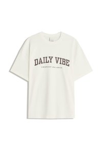 T-shirt en coton blanc avec un texte marron en gras disant "DAILY VIBE" et un texte plus petit "EMBRACE BALANCE" ; coupe décontractée et oversize.