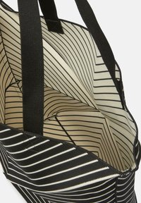 Borsa a mano a righe bianche e nere con manici robusti, dotata di una fodera interna a righe coordinata e un ampio scomparto principale.