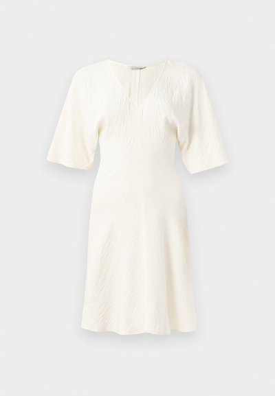 Λευκό, κοντομάνικο φόρεμα με V-ντεκολτέ και υφή υφάσματος. Φαρδιά σιλουέτα με μήκος μέχρι το γόνατο και μια διακριτική πτυχωτή υφή.