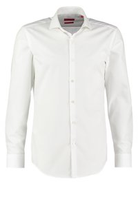 Biała koszula z długim rękawem wykonana z gładkiej tkaniny. Posiada kołnierzyk w szpic, pełne zapięcie na guziki oraz zaokrąglony dół. Mankiety zapinane na pojedynczy guzik.