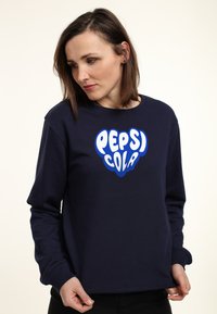 Felpa blu navy, presenta un grande logo "Pepsi Cola" bianco e blu sulla parte anteriore, scollatura rotonda, polsini a costine e vestibilità rilassata.