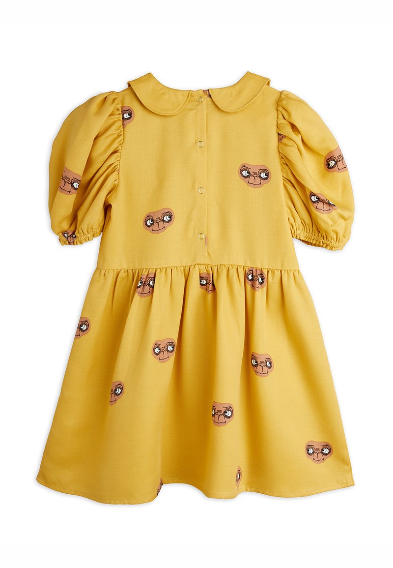Kollane kleit puffvarrukatega, ümmarguse kaelusega ja nööbiga ees. Kangas on kaunistatud suurte silmadega trükitud nägude korduvate mustritega. Pehme tekstuur.