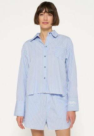 Hellblau gestreiftes Schlafanzug-Set aus weichem Stoff, bestehend aus einem Hemd mit Knopfleiste und einer Tasche sowie passenden Shorts mit umgeschlagenen Ärmeln.