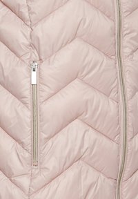 Veste matelassée rose clair avec un motif en chevrons, dotée d'une fermeture éclair argentée et d'une texture lisse et brillante.