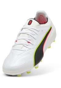 Valkoinen jalkapallokengän naula, jossa musta ja neonkeltaisen Puma-logo, valkoiset nauhat ja punainen "KING"-etiketti kielessä, vinosti vasemmalle.