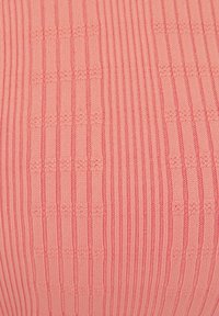 Knitted fabric in a soft pink hue with vertical ribbed texture and subtle patterns, featuring alternating thicker and thinner stripes.