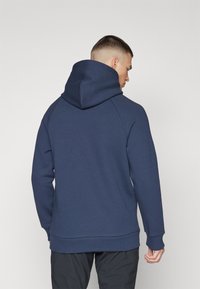 Hoodie bleu marine avec une grande capuche ajustable, des poignets et un ourlet côtelés. Fabriqué à partir d'un tissu doux et texturé avec des manches raglan.