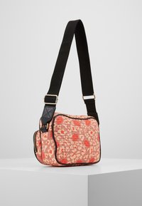 Borsa quadrata a motif rosa e crema con tracolla nera, dotata di chiusura a zip e superficie testurizzata, con bordi a contrasto.