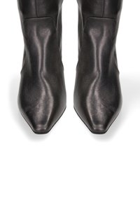 Stivaletti neri in pelle con design a punta, texture liscia e minimo hardware. Presentano una silhouette superiore strutturata.
