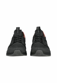 Scarpe sportive nere con una tomaia in mesh testurizzato, dettagli rossi a contrasto e punta arrotondata. Presentano lacci e una suola in gomma.