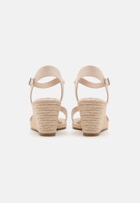 Nahé wedge sandály s tkaným jute podpatkem, měkkými semišovými popruhy a nastavitelnou prackou na kotníku pro bezpečné upevnění. Design s otevřeným zadním dílem.