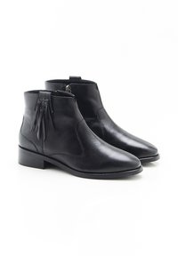 Botas de tobillo de cuero negro con cierre lateral y flecos decorativos, tacón bajo en bloque, punta afilada, sobre un fondo blanco.
