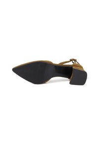 Scarpa con tacco alto in suede color sabbia con punta affusolata. Presenta una suola in gomma nera e una cinghia alla caviglia. Texture liscia senza motivi visibili.