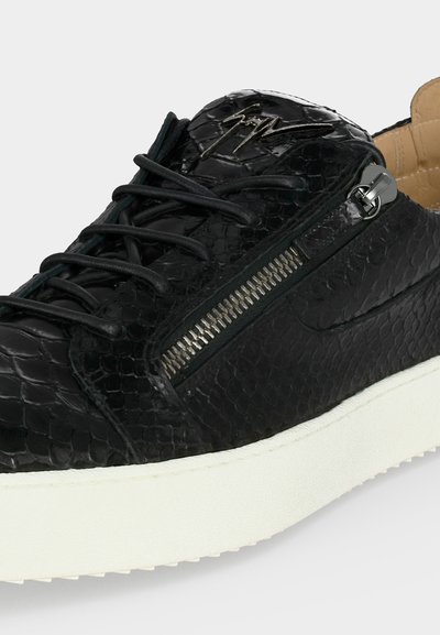 Μαύρο υφασμάτινο δερμάτινο αθλητικό παπούτσι με μαύρα κορδόνια, ασημένιο πλαϊνό φερμουάρ, λευκή σόλα και χαρακτηριστικό μεταλλικό λογότυπο στη γλώσσα.