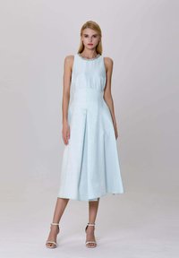 Robe sans manches bleu clair avec une jupe plissée et un tissu texturé, comportant un col perlé et une silhouette évasée.