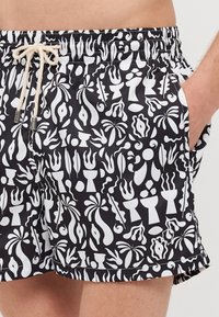 Schwarze Badeshorts mit einem weißen abstrakten Muster aus verschiedenen Formen. Elastischer Bund mit Kordelzug und seitlichen Taschen.
