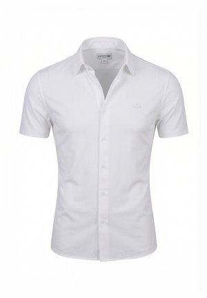 Camicia bianca a maniche corte con bottoni e colletto classico, con delicato logo Lacoste ricamato sul petto a sinistra.