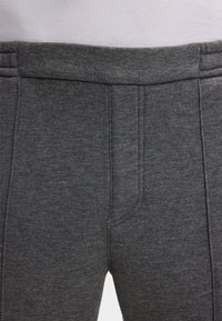Nahaufnahme von grauen Strickhosen mit elastischem Bund und vertikalen Nahtdetails auf der Vorderseite.