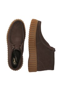 Bruine suède enkellaarzen met een gestructureerde rubberen zool, met een eenvoudig ontwerp, elastische veters en contrasterende stikseldetails.