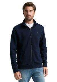 Granatowy rozpinany sweatshirt z teksturowanej tkaniny. Wyposażony w boczne kieszenie, ściągacze na mankietach oraz małe logo na klatce piersiowej. Luźny krój.