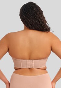 Sujetador sin tirantes de color beige con acabado texturizado y cierre de gancho y ojal en la parte trasera, diseñado para una silueta suave.