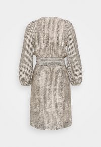 Beige klänning med svart prickmönster, långa puffärmar, åtsittande midja och rak skärning. Tillverkad av lättviktsmaterial.
