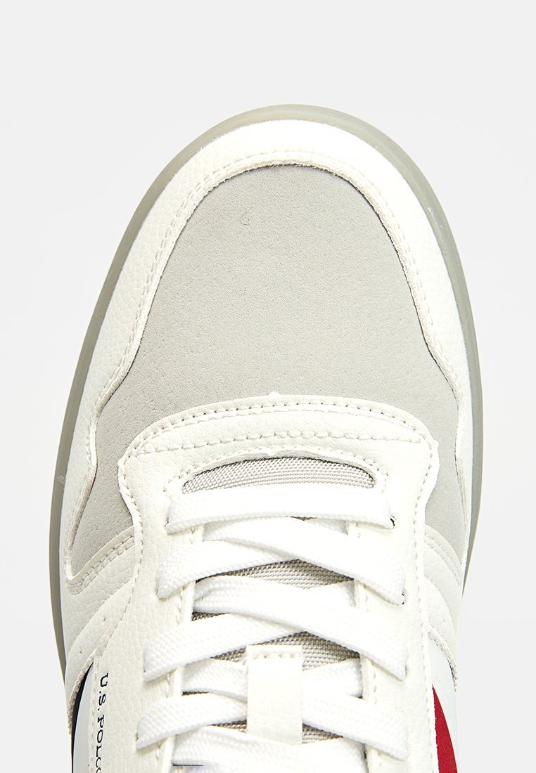 Baskets blanches avec une tige en cuir et en suède gris, doublure texturée et accents rouges. Elles sont dotées de lacets blancs et d'une semelle en caoutchouc.