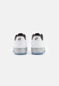 Sneakers Nike Air bianche con dettagli argentati, punta arrotondata, collo imbottito e suola in gomma traslucida, viste da dietro.