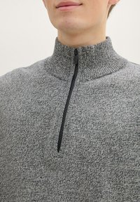 Gray zip-up sweater featuring a high neck, textured fabric, and a black zipper. The knit pattern adds depth to the overall design.