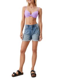 Lila Bikini-Oberteil mit einem Dreh-Detail, kombiniert mit hellblauen Denim-Shorts mit umgeschlagenen Säumen und schwarzen Sandalen mit geflochtenen Akzenten.