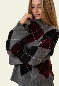 Argyle-Pullover in Grau, Schwarz und Burgunderrot. Weiches Strickmaterial mit gerippten Bündchen und Saum. Hoher Kragen. Gemütlicher, lockerer Schnitt.