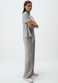 Grijze, gestructureerde gebreide lounge-set met een T-shirt met korte mouwen en een hoge kraag en een ontspannen fit broek met zijzakken. Basis witte sneakers.