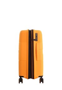 Hard-shell suitcase in vibrant orange with a textured surface, dual zippers, side handle, and four wheels for easy mobility.