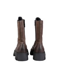 Brown leather ankle boots with a chunky black sole, featuring side zippers and stitched detailing along the seams.