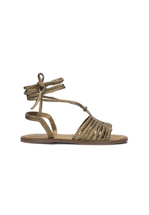 Flat sandals met een gevlochten ontwerp in metallic goud. Heeft enkelbandjes en gestreepte details op de voetbed. De zool lijkt lichtgewicht.