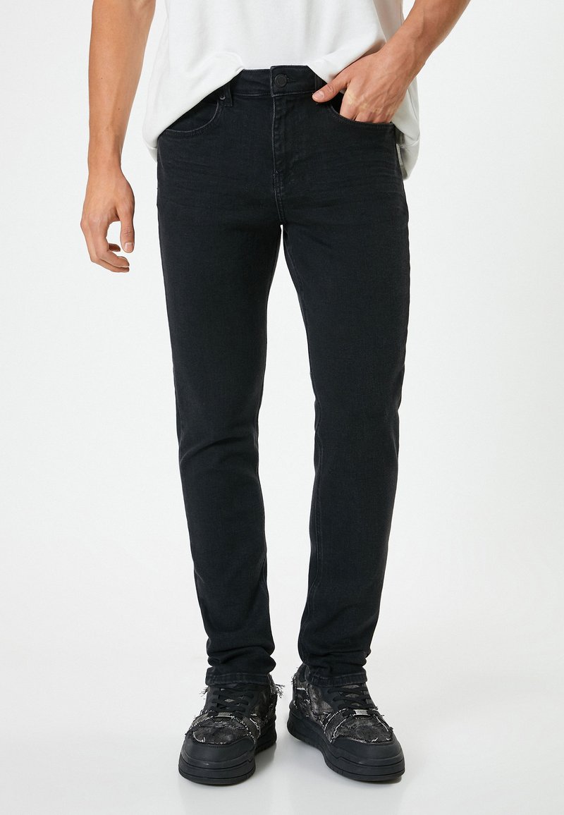 Jeans neri slim-fit realizzati in denim, con un classico design a cinque tasche, chiusura con bottone e una leggera texture sbiadita.