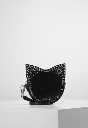 Sac bandoulière noir en forme de chat avec des clous argentés soulignant les oreilles, les yeux et les bords, avec une bandoulière amovible et une quincaillerie argentée.