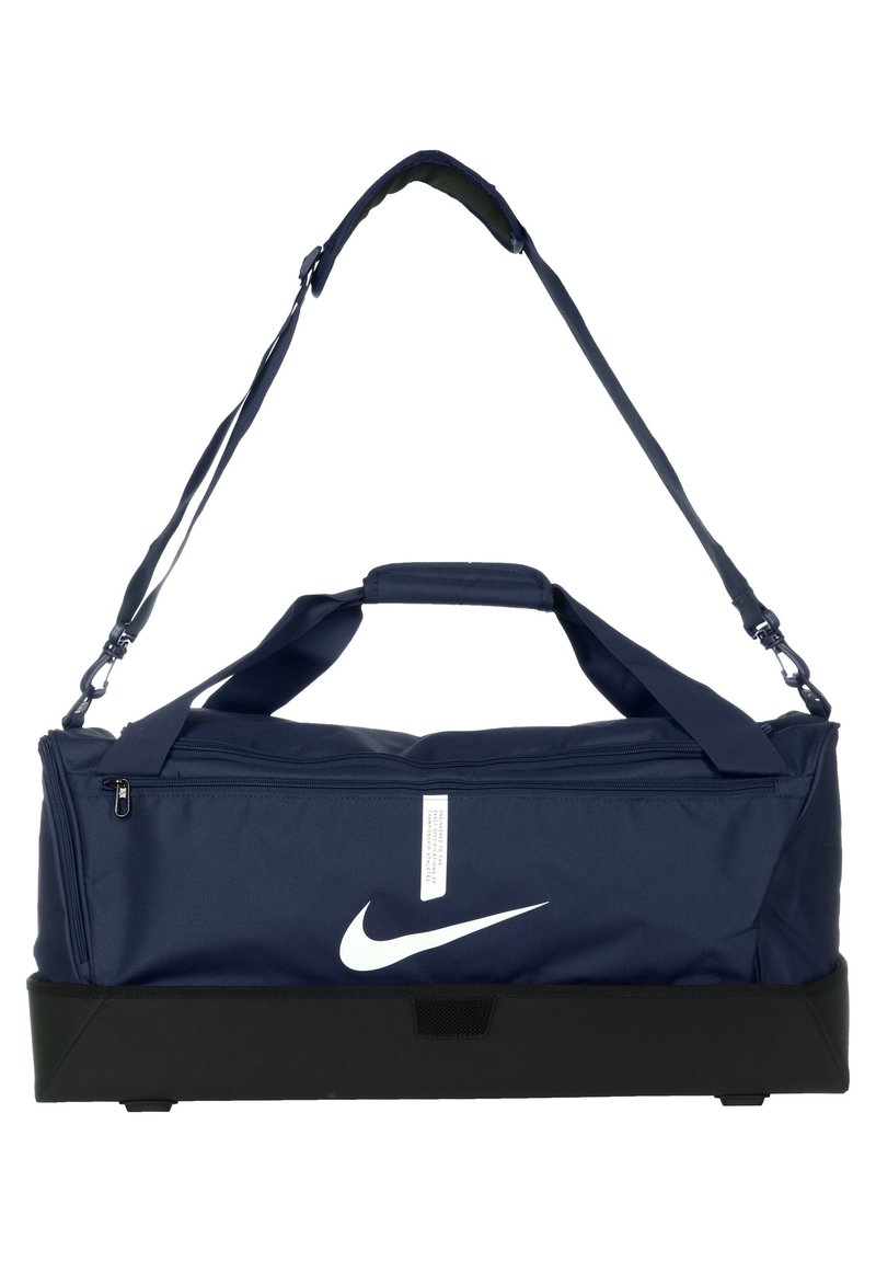 Marineblauwe duffelbag met een wit Nike-logo, voorzien van een ritssluiting, gewatteerde handgrepen en een verstelbare schouderband. Zwarte basis voor duurzaamheid.