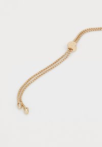 Zlatý řetízek náramek s dvojitými řetězci, vybavený kulatým zapínáním s rytím "RL" a kapkovými konci. Hladký povrch, lesklý finiš.