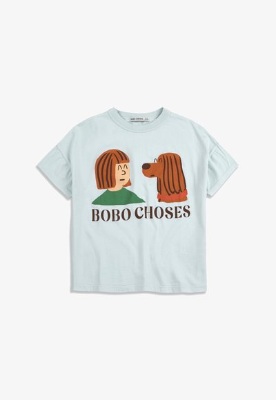 Jasnoniebieska koszulka z krótkim rękawem z grafiką osoby o brązowych włosach i brązowego psa zwróconych do siebie twarzami, nad napisem "BOBO CHOSES".