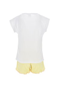 Camiseta blanca de manga corta con cuello redondo, combinada con unos pantalones cortos amarillos que tienen un dobladillo con forma de onda y acentos naranjas.