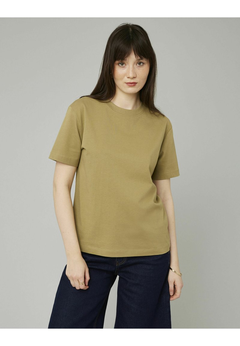 T-shirt en coton à manches courtes de couleur kaki, avec un col rond et une coupe décontractée, associé à un jean ample bleu foncé.