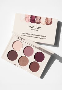 Creach Peach eyeshadow palette with six circular pans in shades of pink, mauve, and burgundy; includes a shimmery brown. Sleek white case.