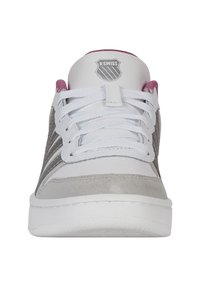 Fehér és szürke sneaker, amely velúr és hálós anyagokból készült, lapos fűzőkkel és rózsaszín kiegészítővel a nyakban; a nyelvén K-Swiss logó található.