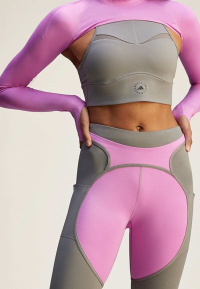 Top y leggings deportivos en púrpura y gris con un diseño ajustado, textura suave y paneles de colores contrastantes en ambas prendas.
