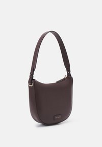 Sac à bandoulière en cuir brun foncé avec un fond incurvé, une sangle large, une fermeture éclair et une discrète étiquette logo au centre avant.