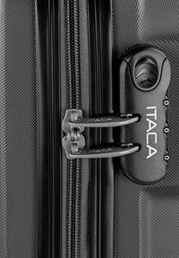 Primer plano del cierre de cremallera de una maleta ITACA negra con dos tiradores bloqueados y cerradura de combinación integrada.