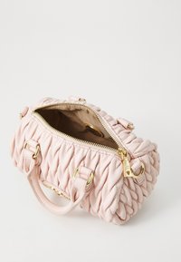 Pink leather handbag featuring a woven texture, gold hardware, dual handles, and a zip closure revealing a beige fabric interior.