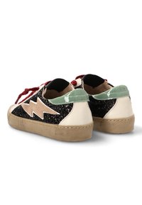 Un par de zapatillas bajas con lados de purpurina negra, diseño de rayo beige, lengüetas traseras verdes, cordones rojos y suelas beige, vistas desde atrás.